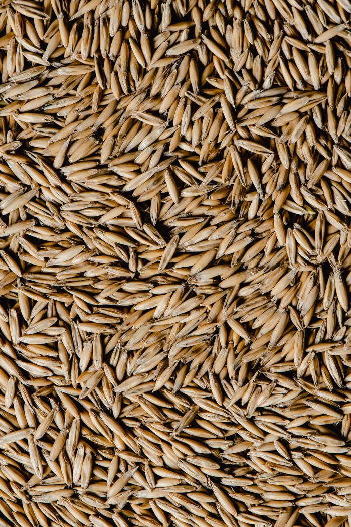 Detailed top view of raw oat grains, showcasing texture and natural patterns.